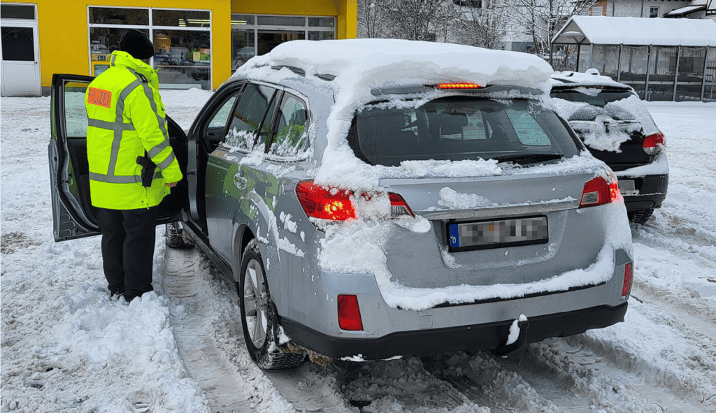 Polizist kontrolliert Auto im Schnee.