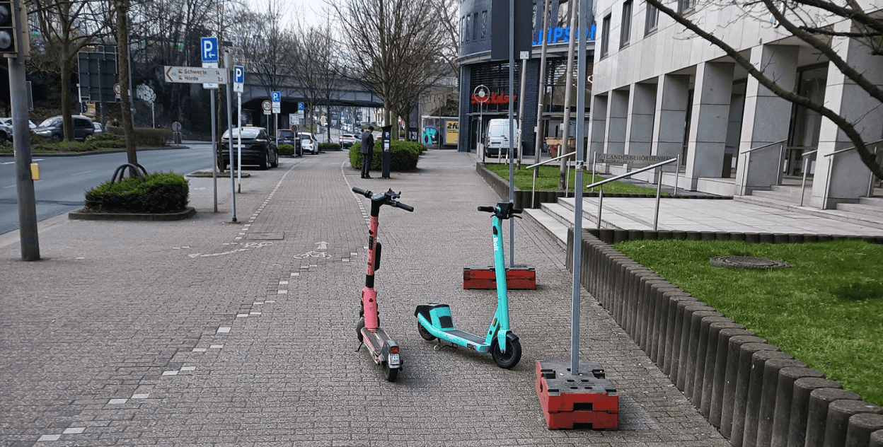 Zwei E-Scooter auf einem Gehweg in der Stadt.