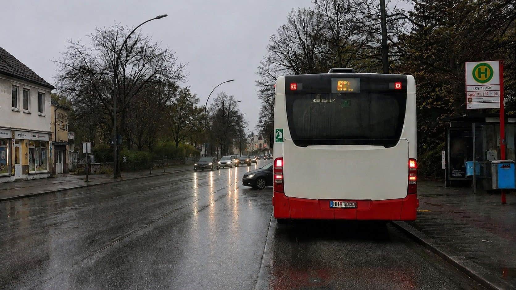 Linienbus an Haltestelle bei Regen in Stadt